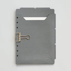 Dark gray planner dividers with a gold clip on a gray background