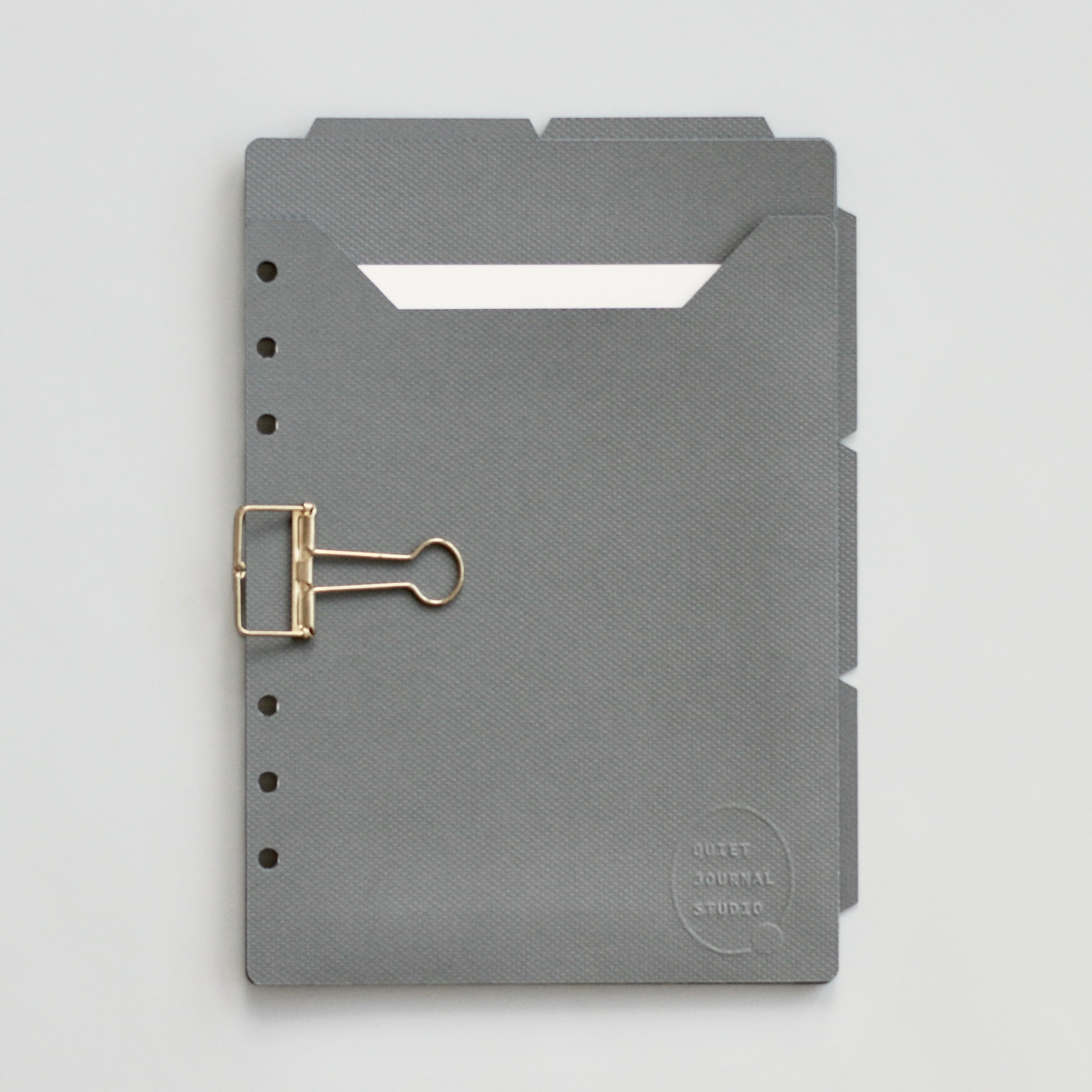 Dark gray planner dividers with a gold clip on a gray background