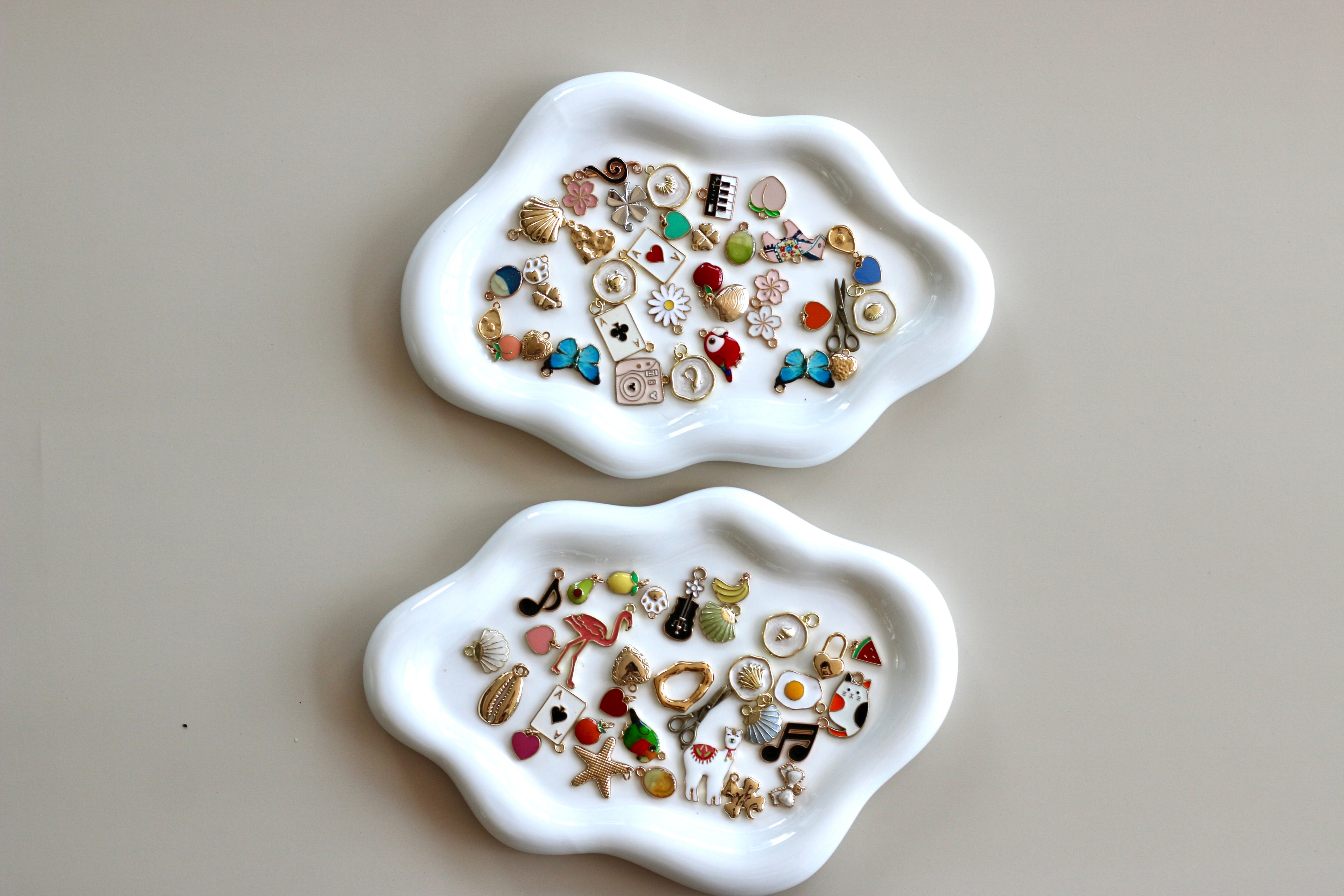 Two white trays with various small decorative items on a light gray background