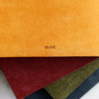 Close-up of leather-bound books with 'quiet' embossed on a marble surface