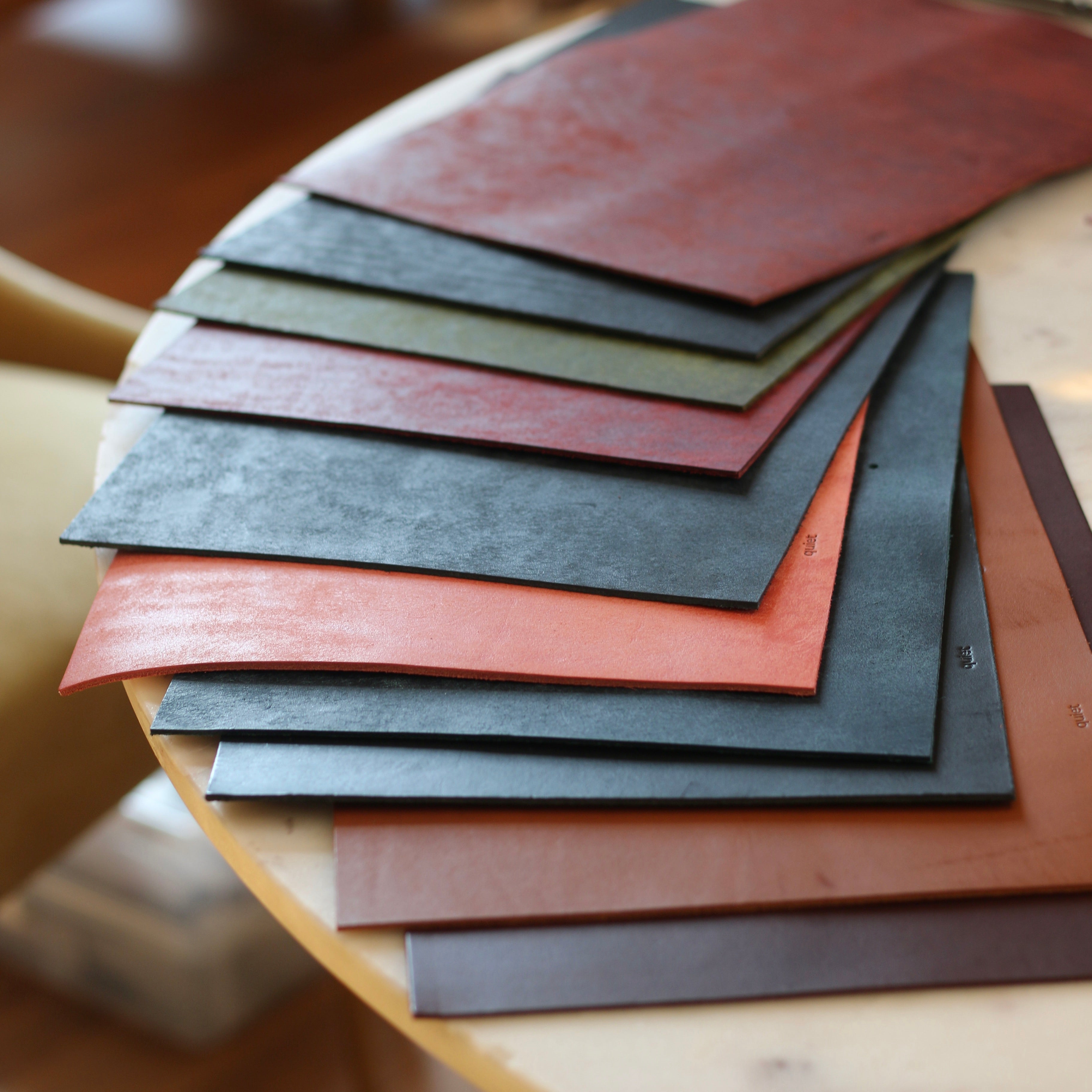 Stack of leather samples in various colors on a wooden surface