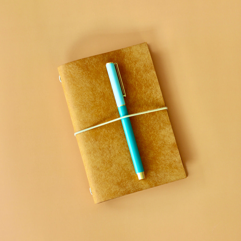 Yellow notebook with a blue pen on a beige background