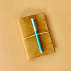 Yellow notebook with a blue pen on a beige background
