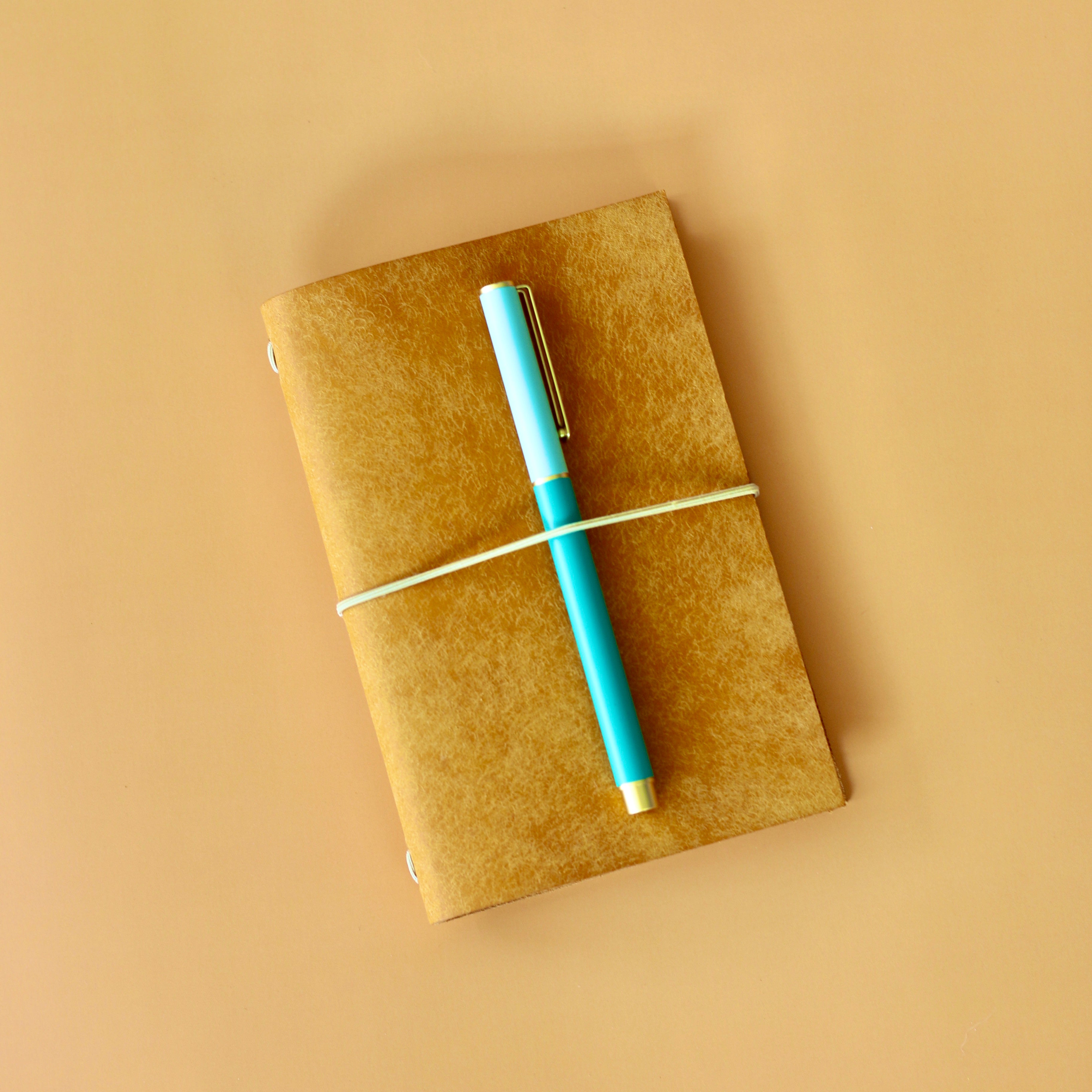 Yellow notebook with a blue pen on a beige background