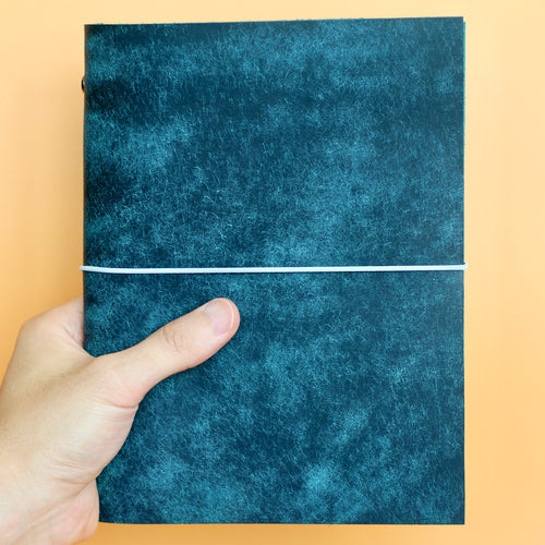 Hand holding a blue textured fabric against a beige background