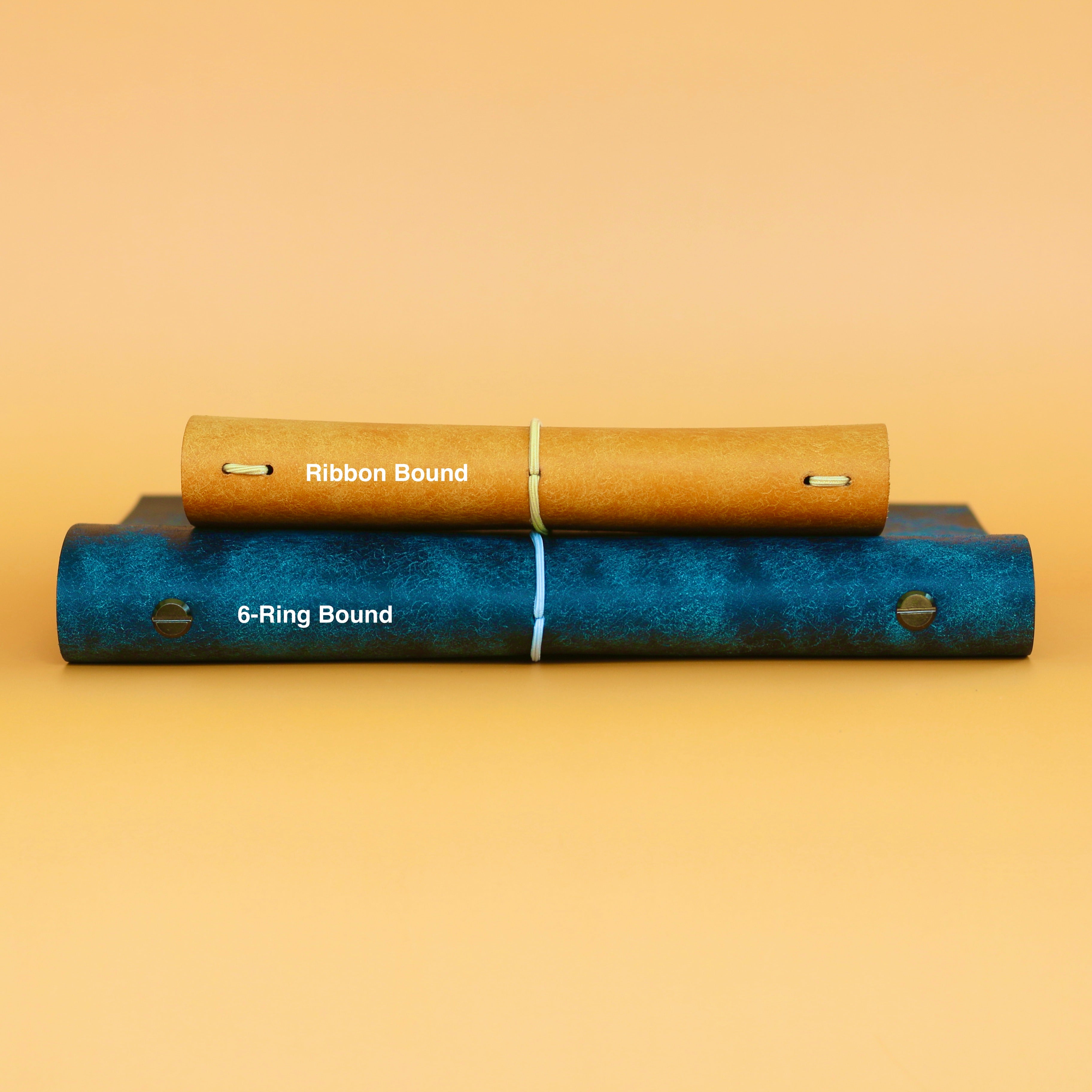 Two books, one ribbon-bound and one 6-ring bound, on a beige background.