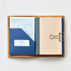 Open notebook with golden clip, showing blue and beige pages.