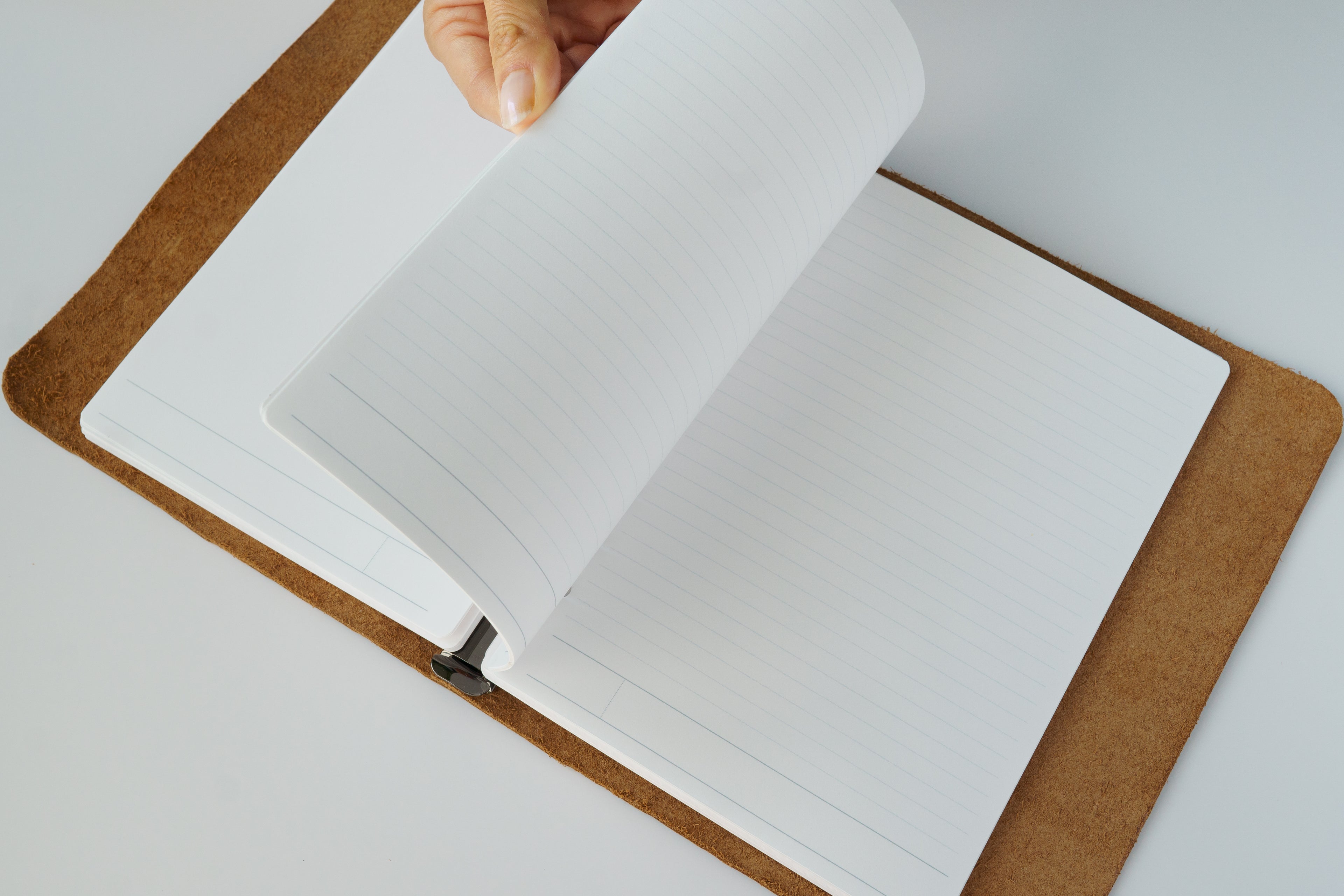 Open notebook with a hand turning a page on a light background