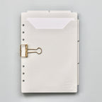 Light gray planner dividers with a gold clip on a gray background