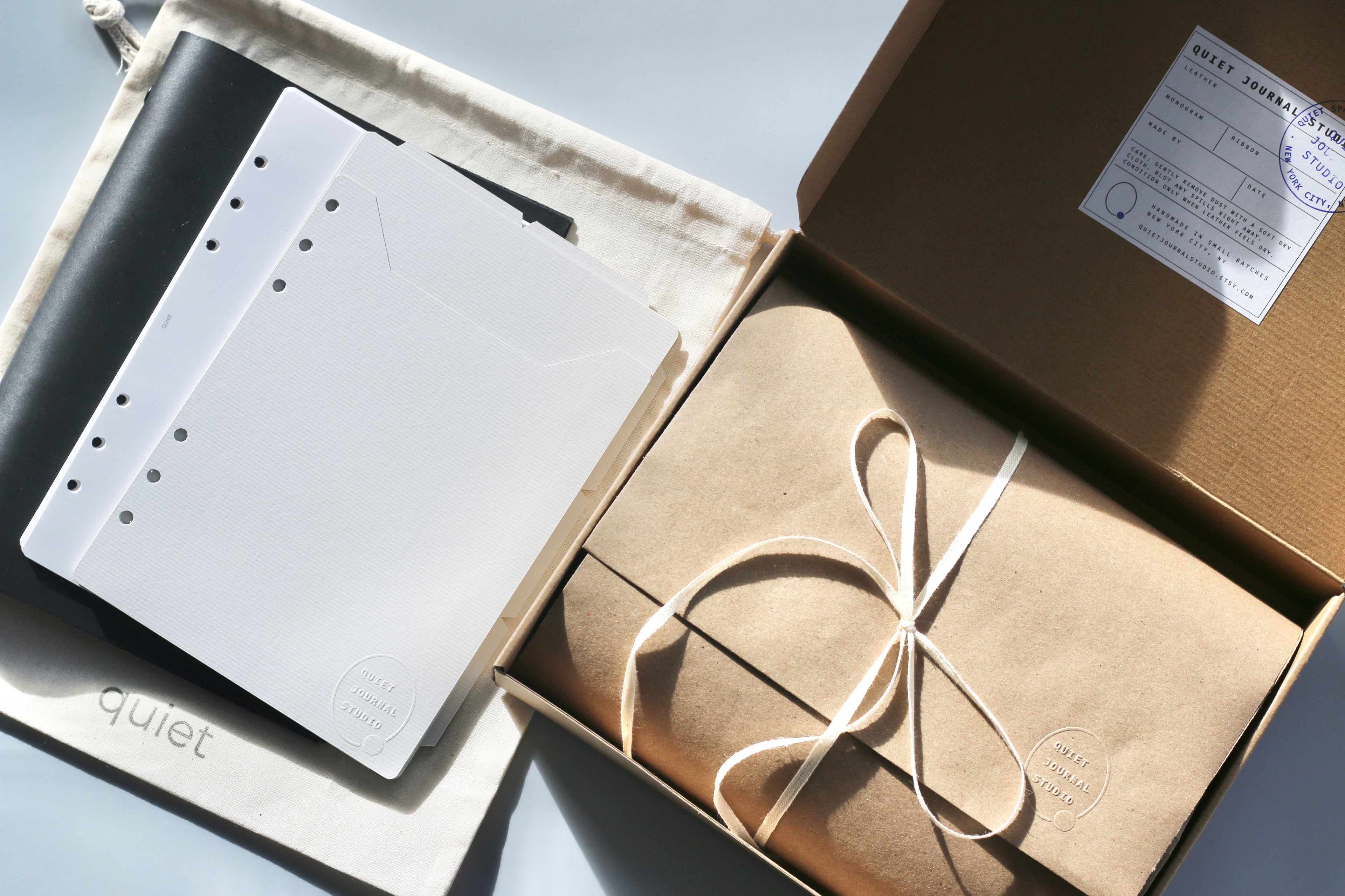 Product packaging with a notebook and white sheets inside an open box.