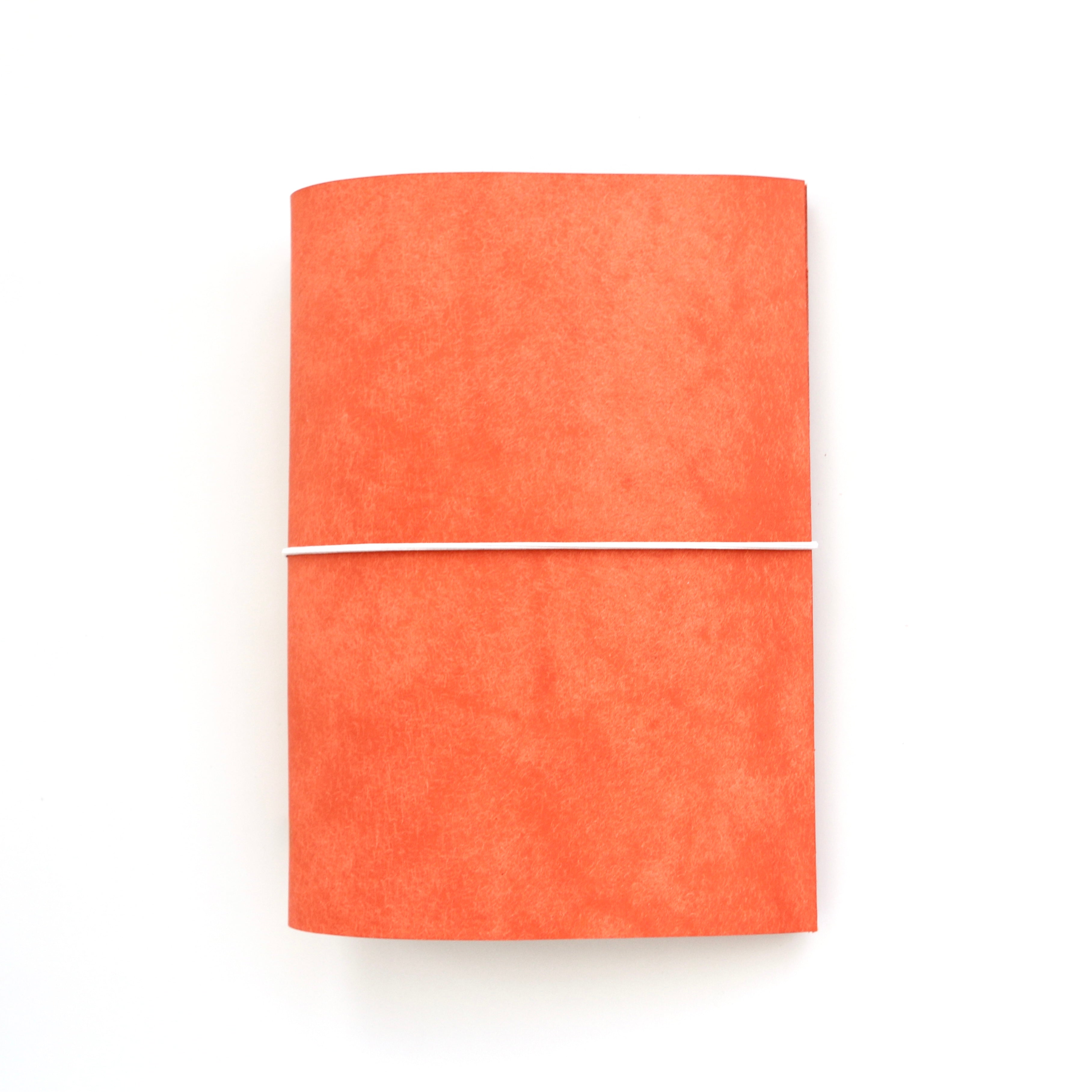 Orange notebook with a white strap on a white background