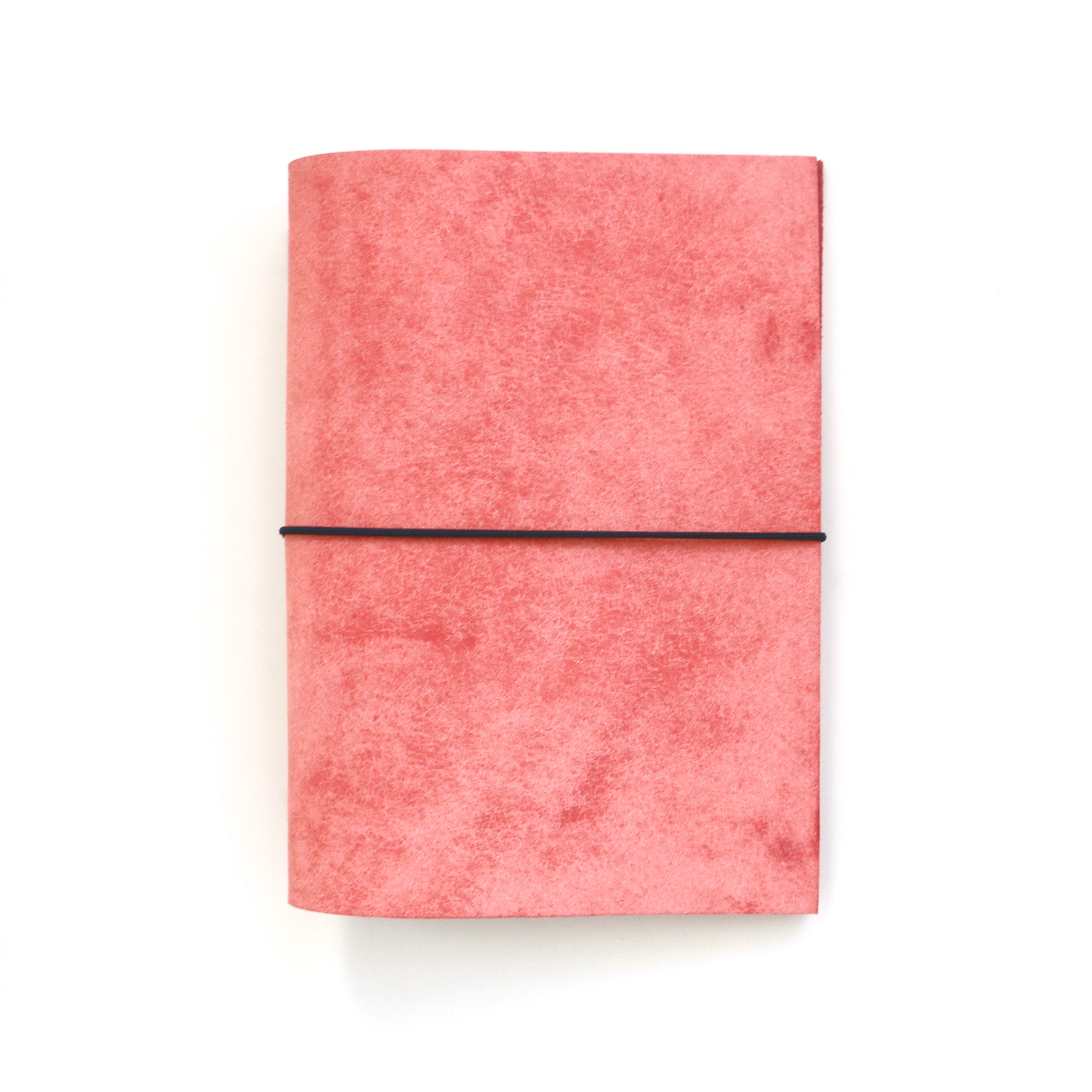 Pink notebook with a black elastic band on a white background